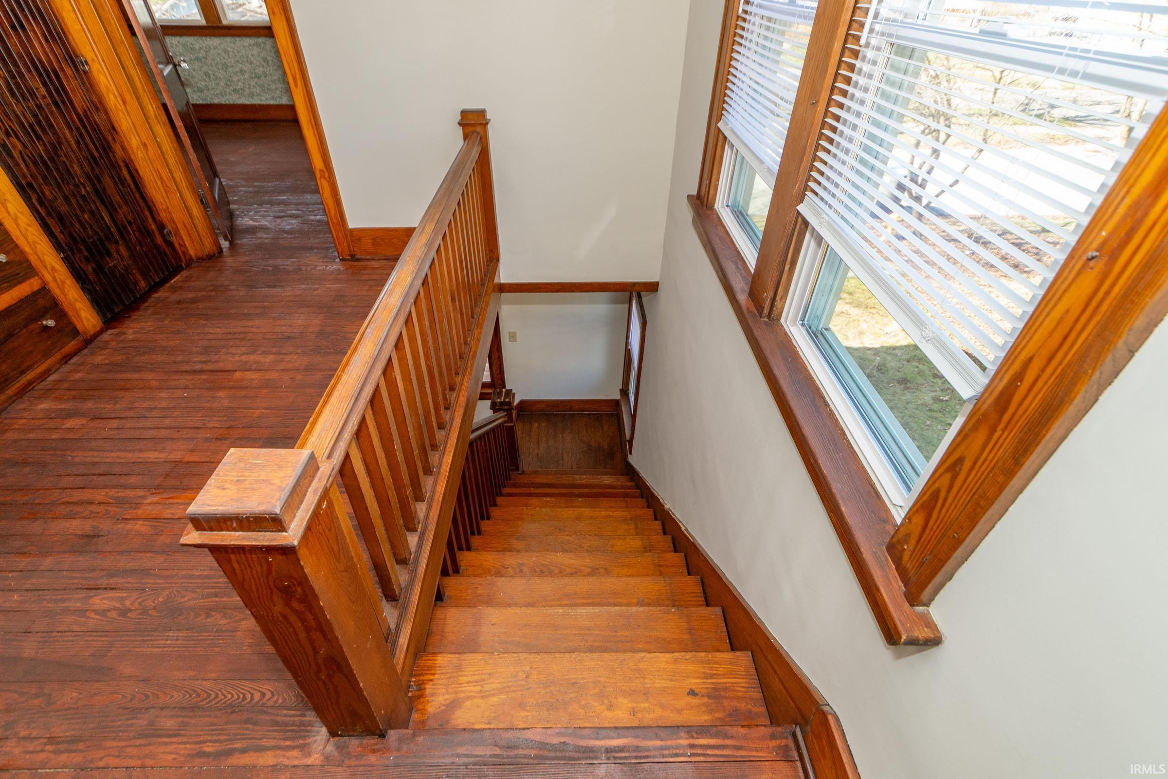 Stairs with wood-type flooring and a high ceiling