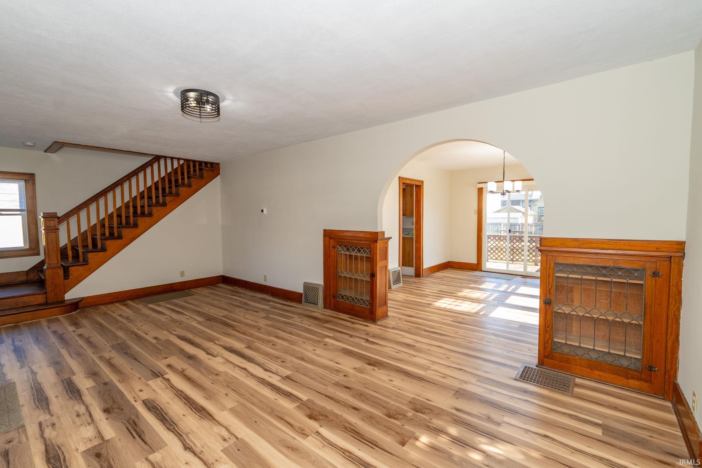 Unfurnished living room with light wood-type flooring, plenty of natural light, and arched walkways