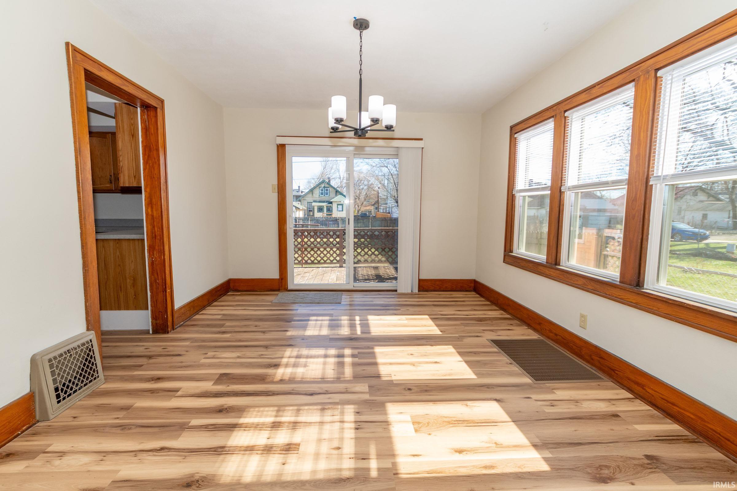 Unfurnished dining area with light wood-style floors, a chandelier, and healthy amount of natural light
