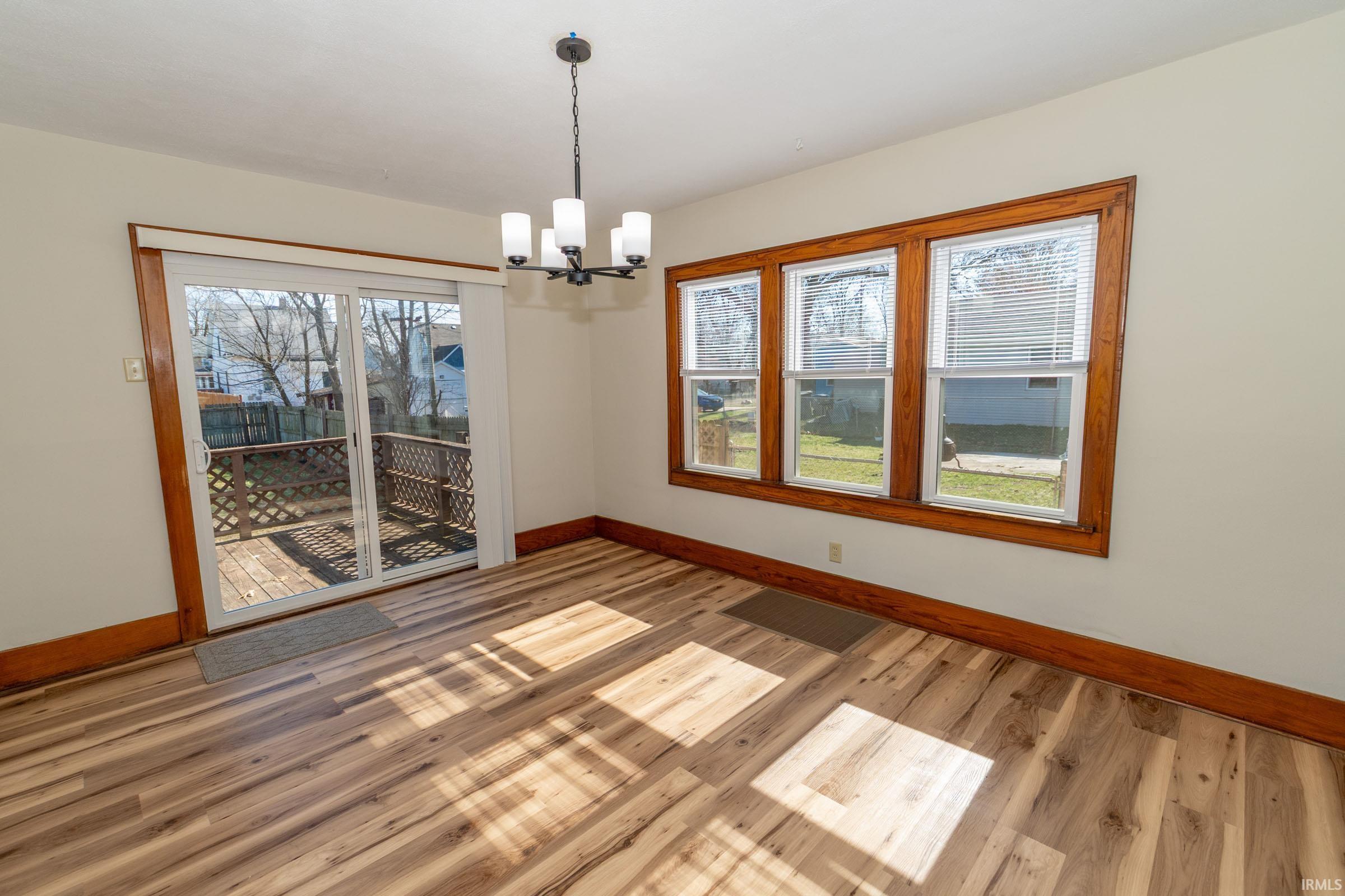 Spare room featuring light wood finished floors and a chandelier