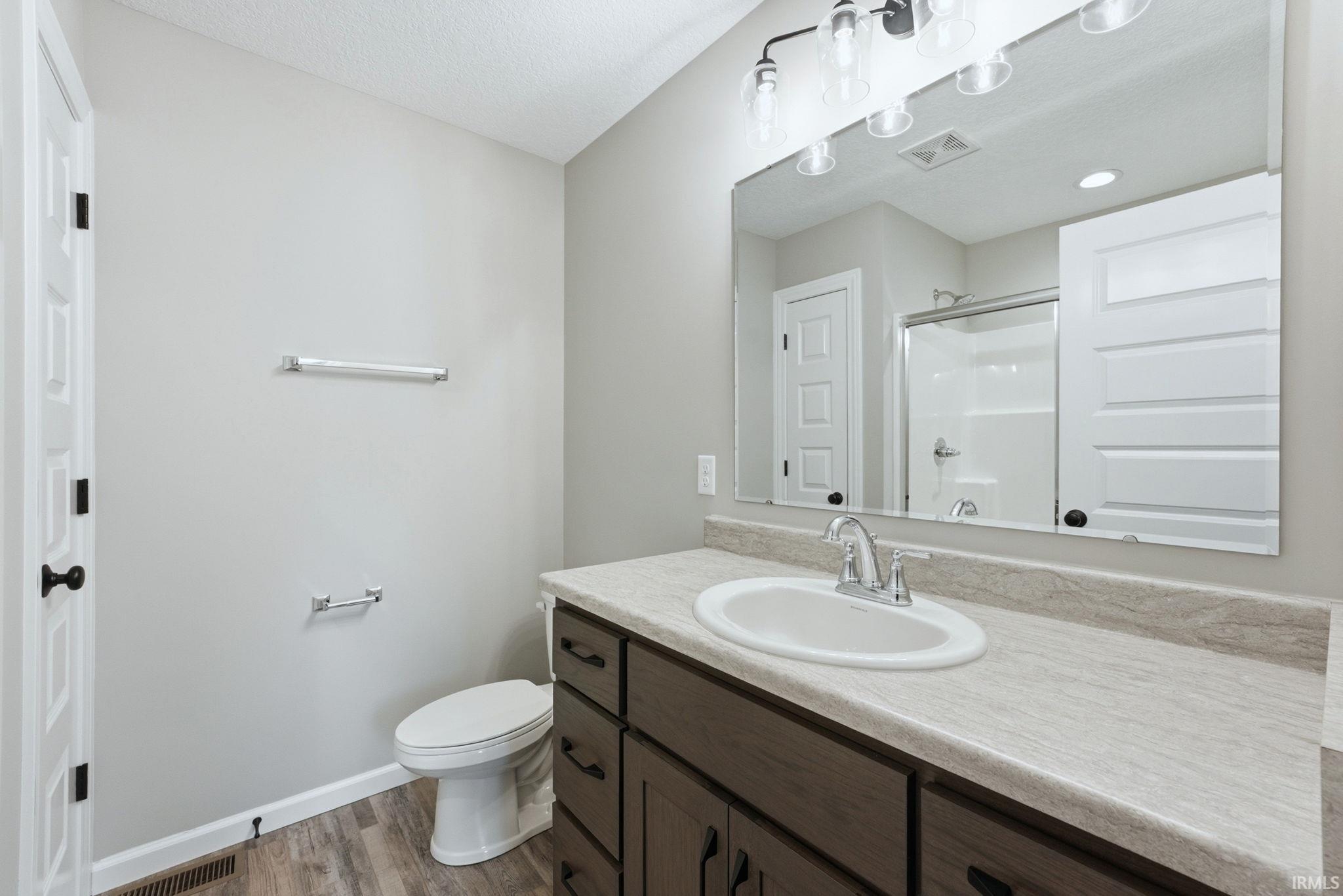 Full bath featuring vanity, a stall shower, and light wood-style flooring