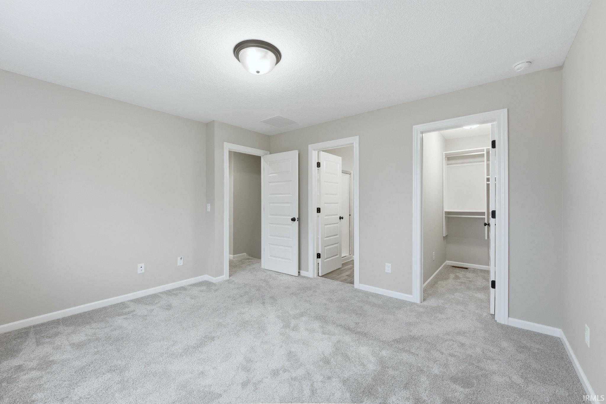 Unfurnished bedroom featuring a walk in closet and light colored carpet