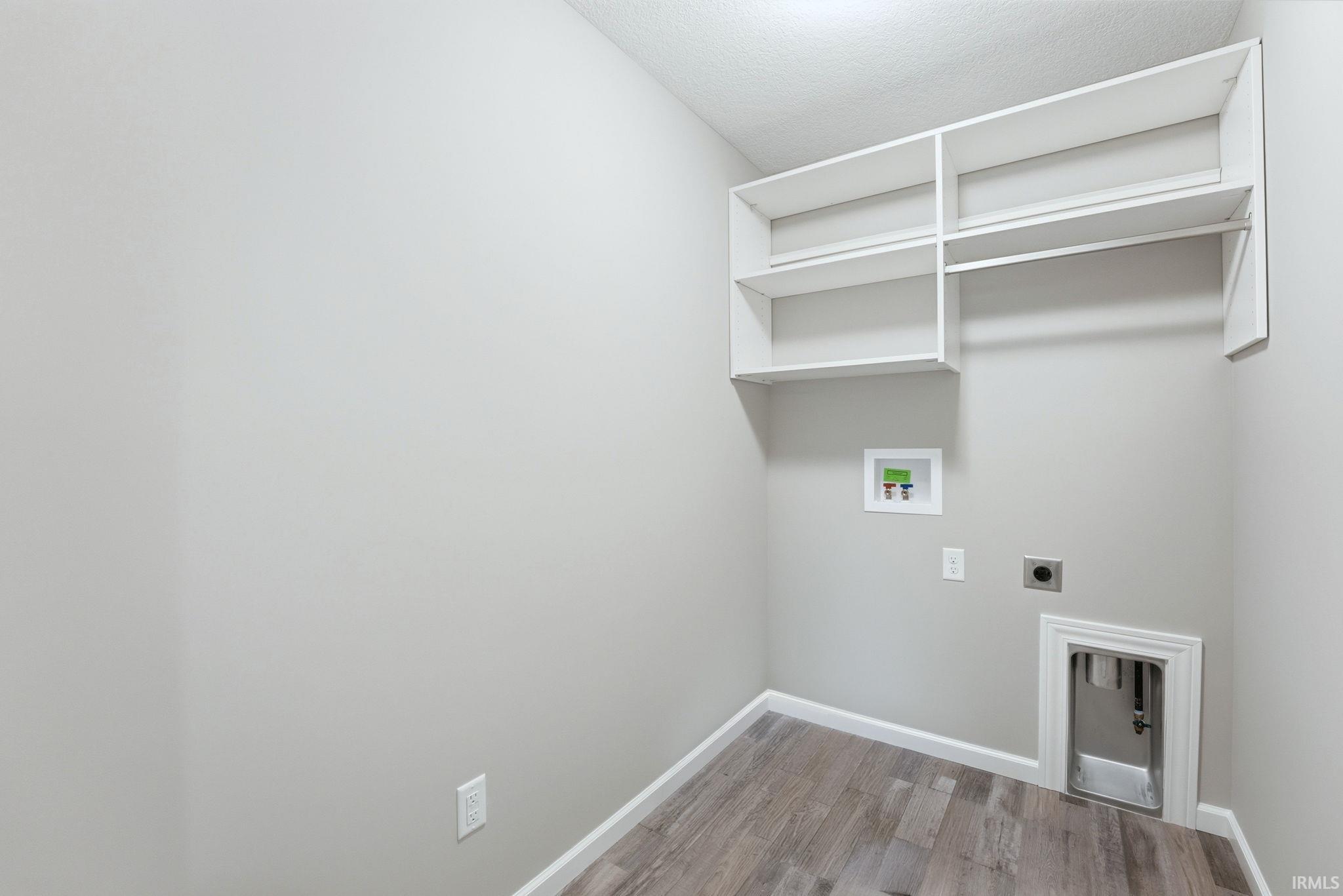 Laundry room featuring hookup for a washing machine, light wood-style flooring, electric dryer hookup, and a textured ceiling