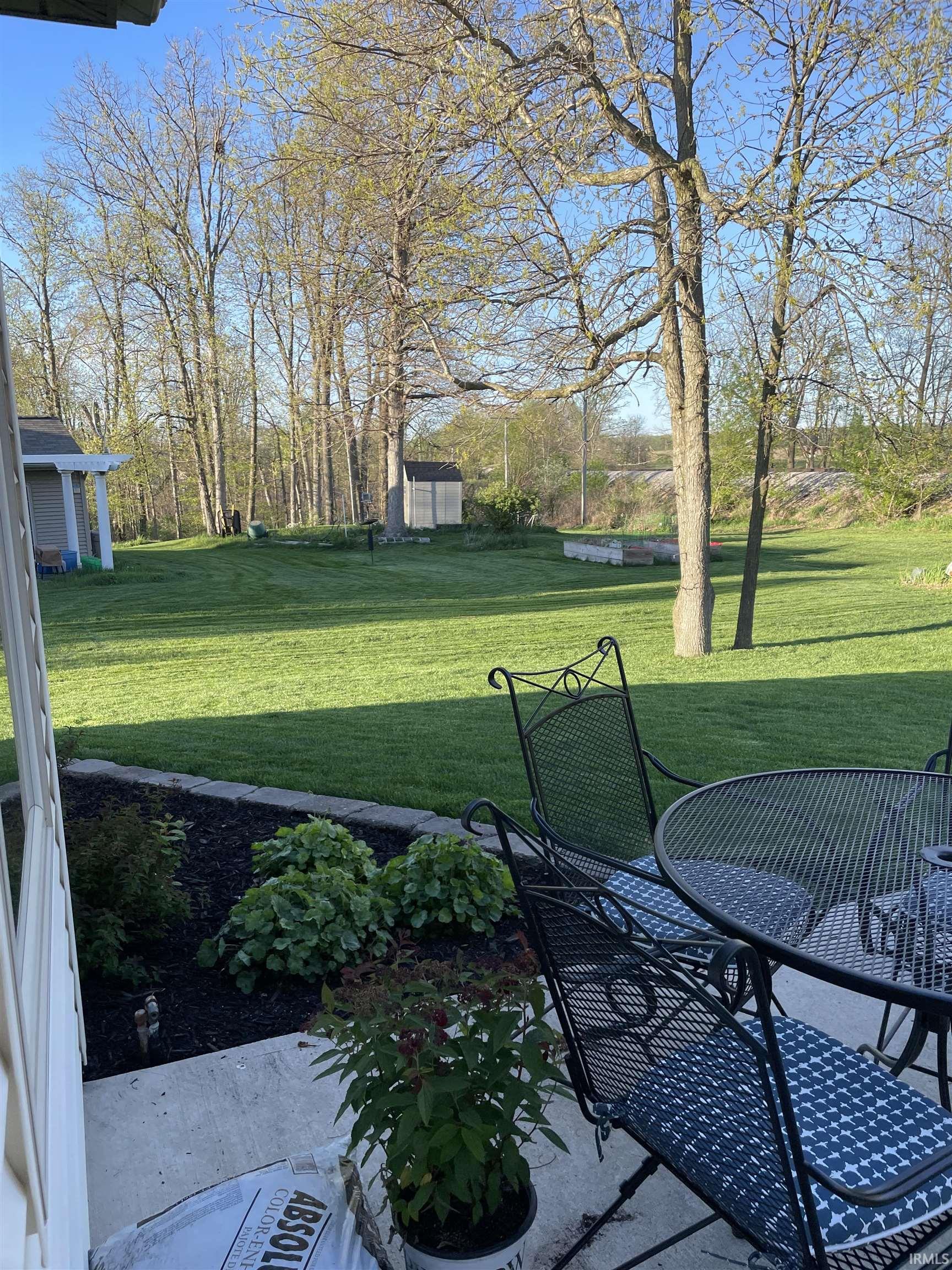 View of green lawn featuring a storage unit and outdoor dining area