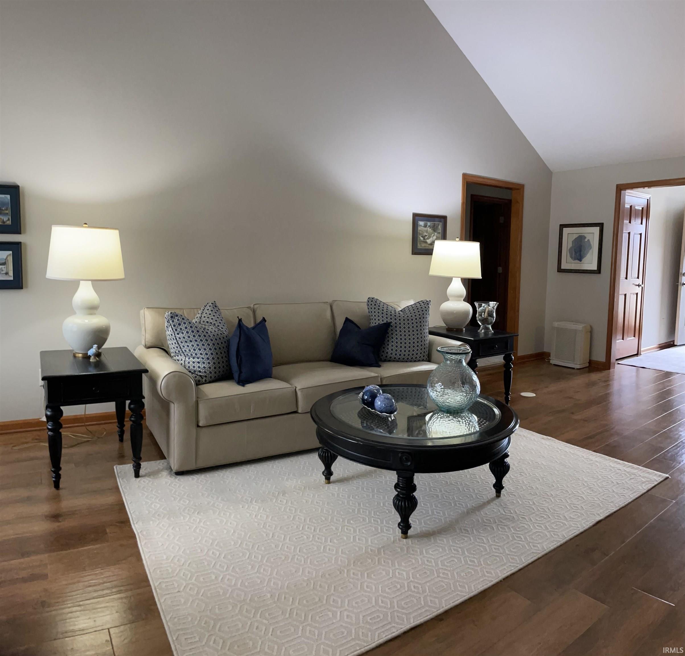 Living room with dark wood-style floors and lofted ceiling
