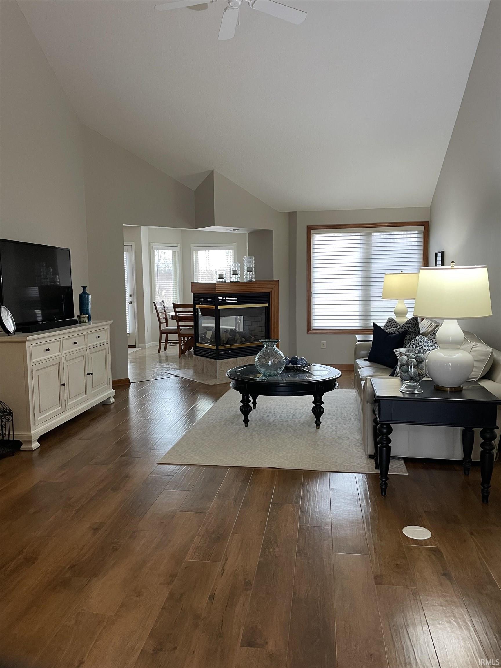 Living area featuring lofted ceiling, dark wood finished floors, and a ceiling fan
