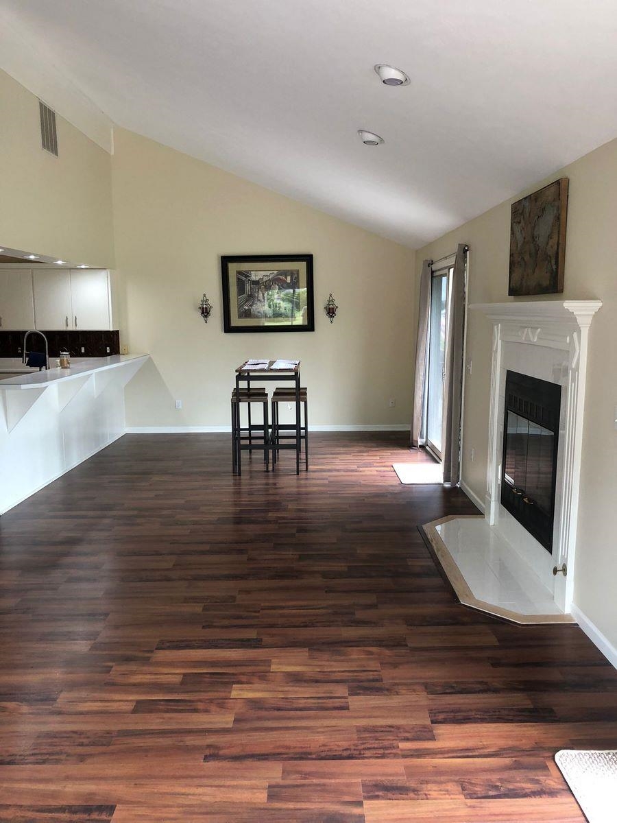 Living room with lofted ceiling, dark wood-style floors, and a fireplace with flush hearth
