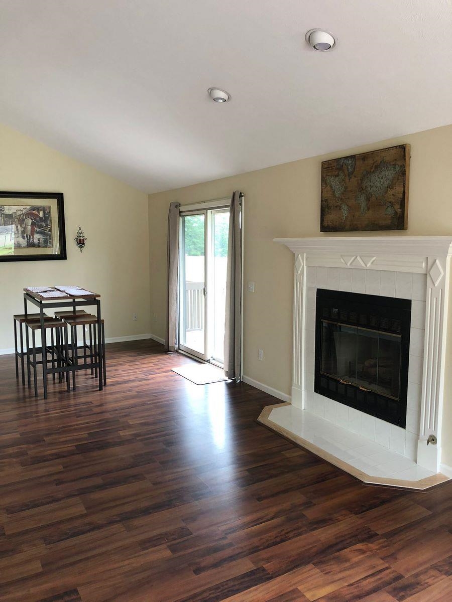 Living room featuring dark wood-style flooring, a fireplace, and lofted ceiling