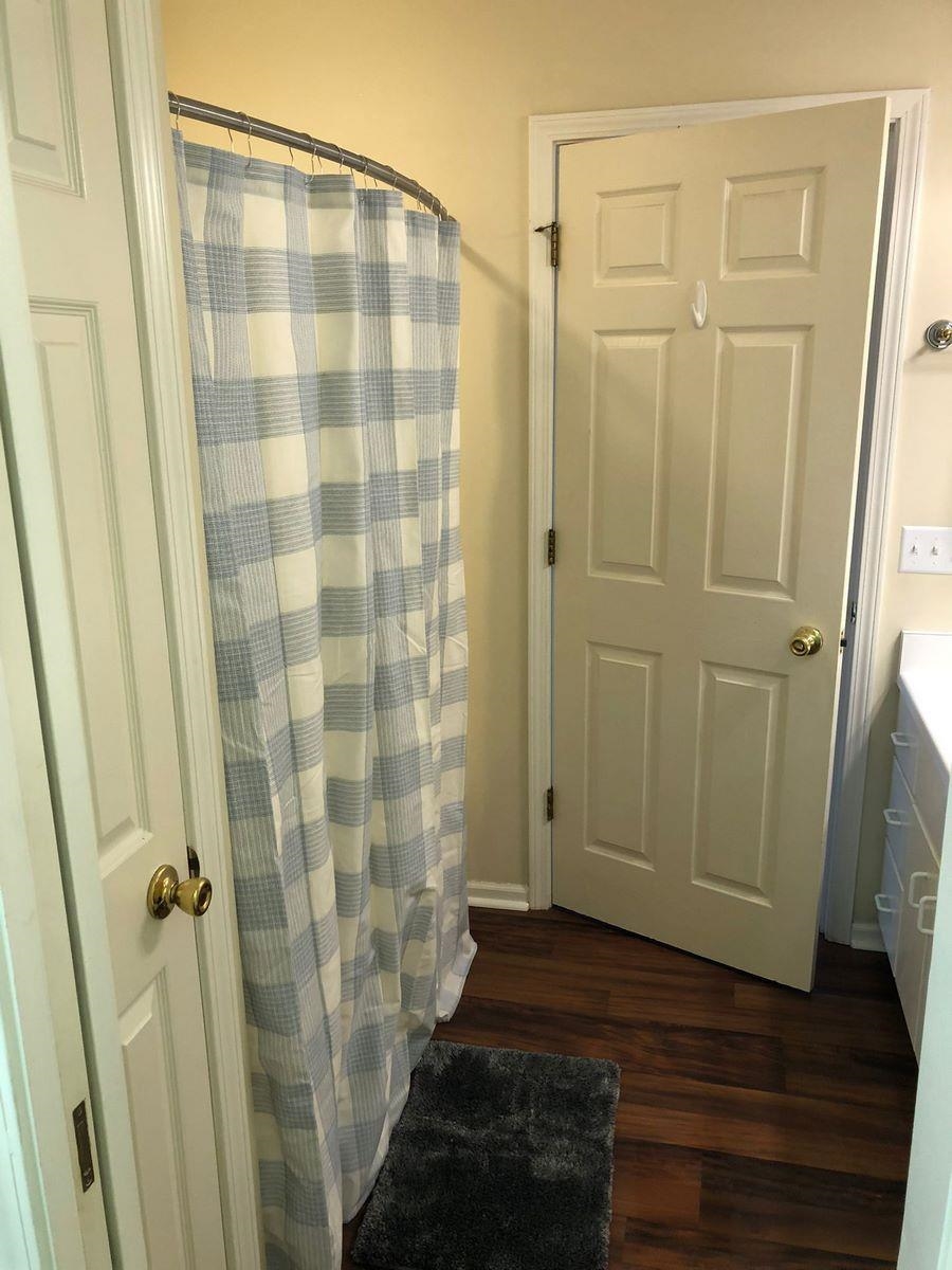 Full bath featuring dark wood-style floors, a shower with shower curtain, and vanity