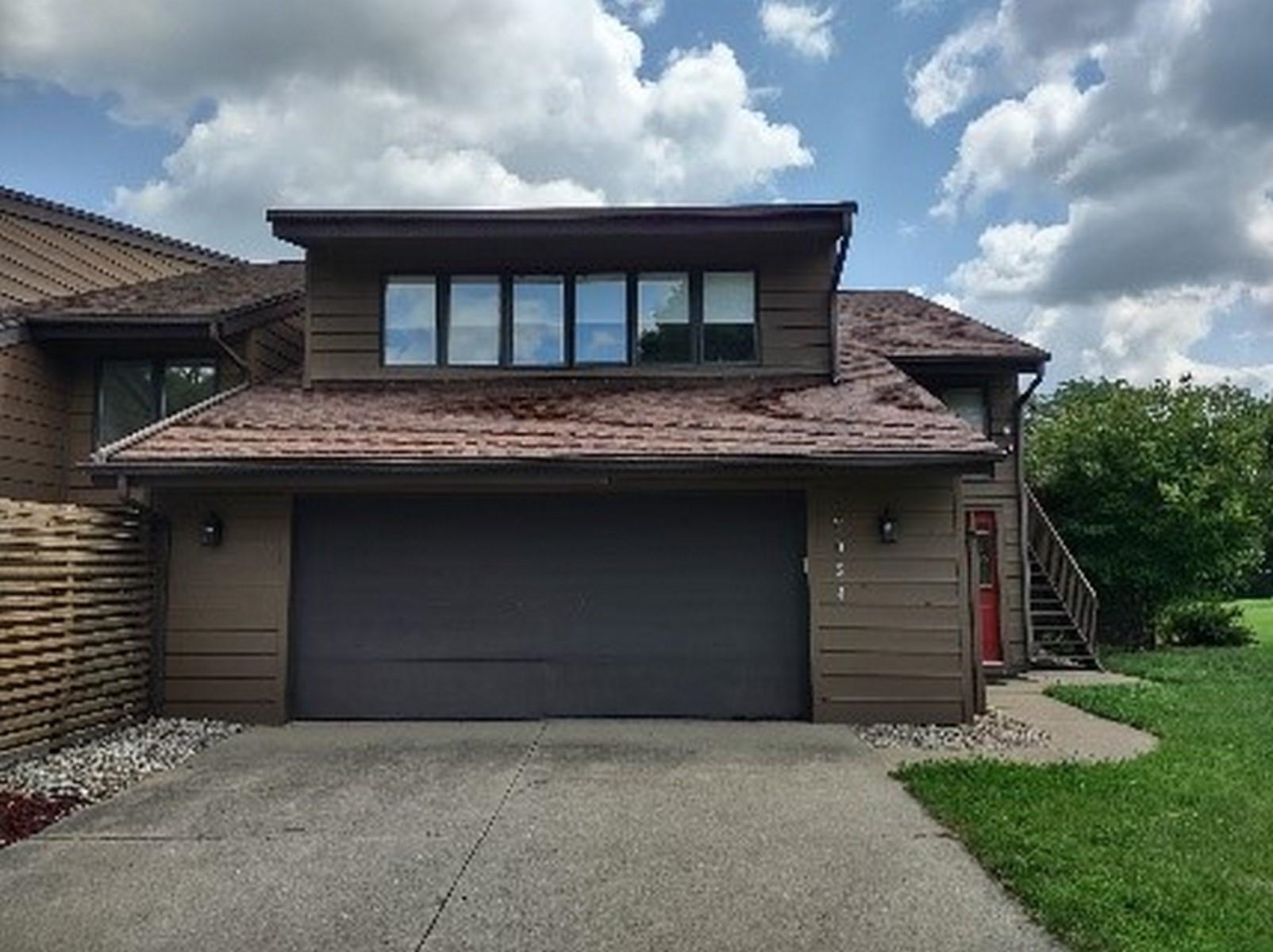 View of side of home featuring an attached garage, driveway, and a yard