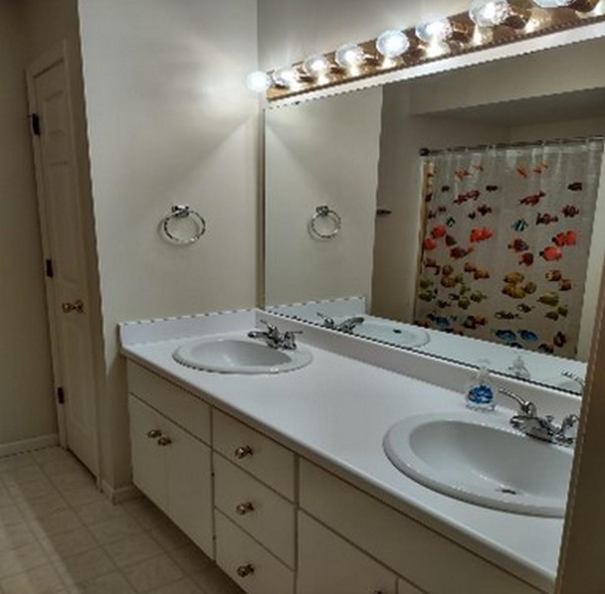 Bathroom with double vanity, curtained shower, and light tile patterned floors