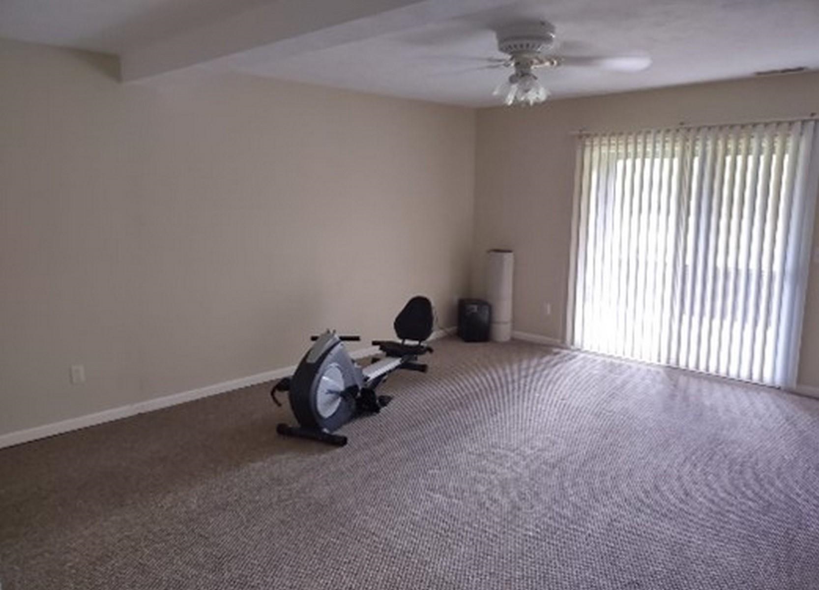 Exercise area featuring ceiling fan, carpet, and beam ceiling