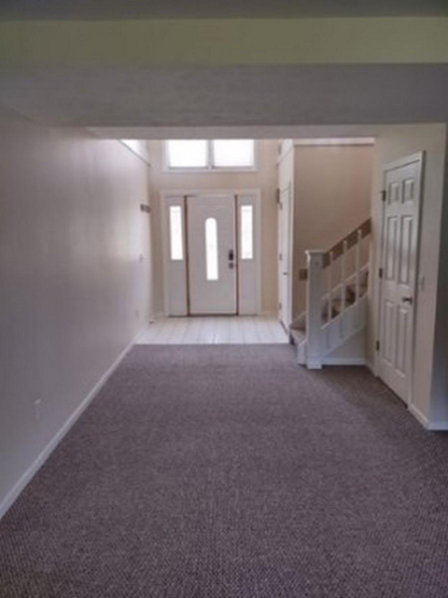Foyer entrance with stairway and carpet flooring