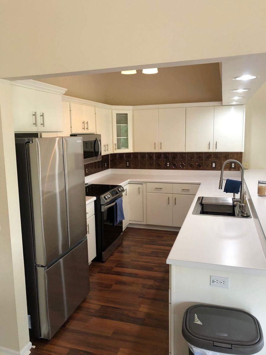 Kitchen with light countertops, stainless steel appliances, and white cabinetry