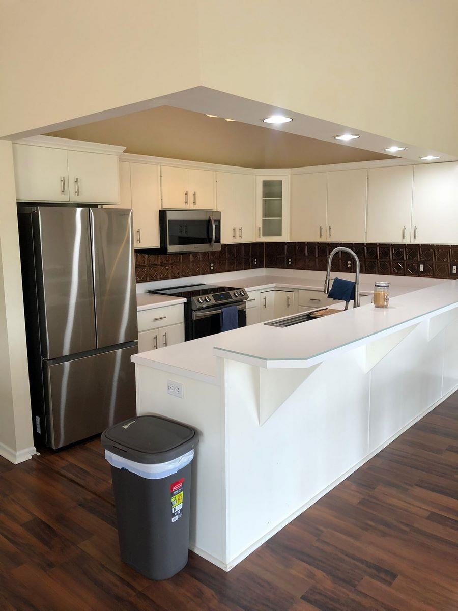 Kitchen featuring stainless steel appliances, light countertops, white cabinetry, dark wood-style flooring, and recessed lighting
