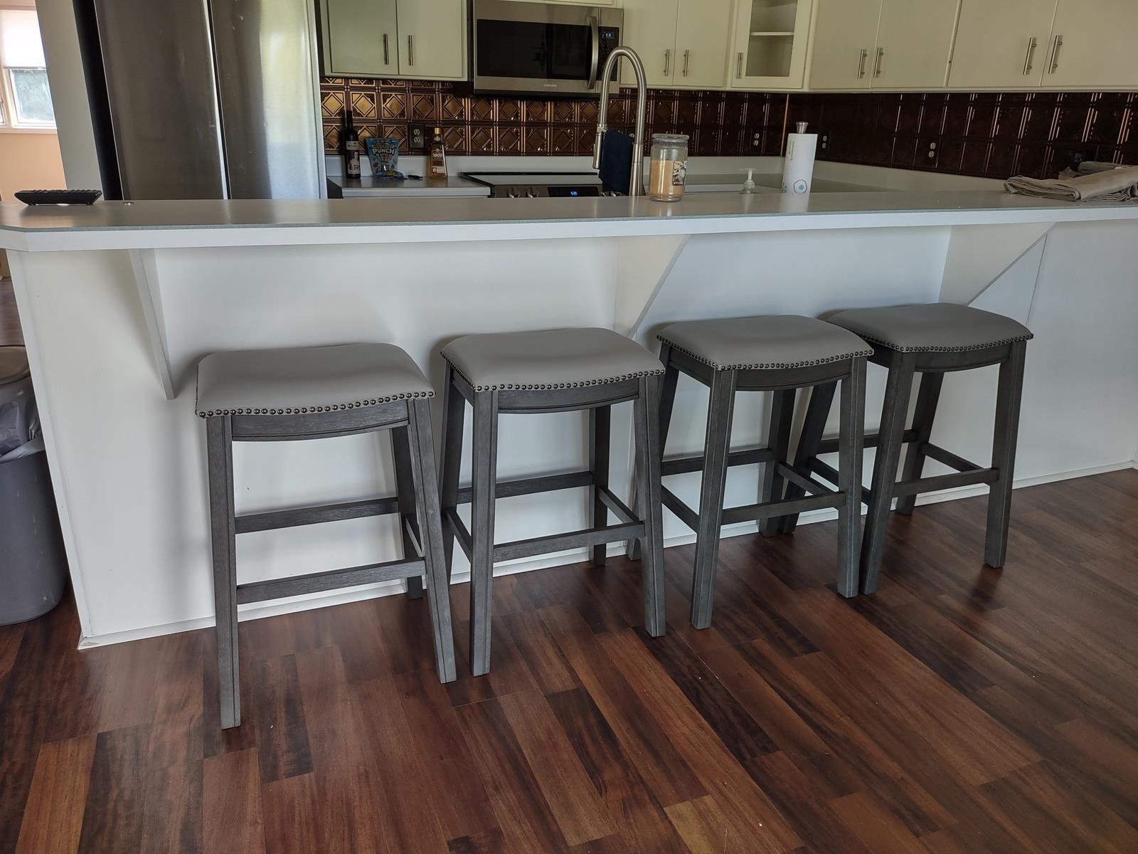 Kitchen with a kitchen bar, stainless steel appliances, glass fronted cabinets, light countertops, and dark wood finished floors