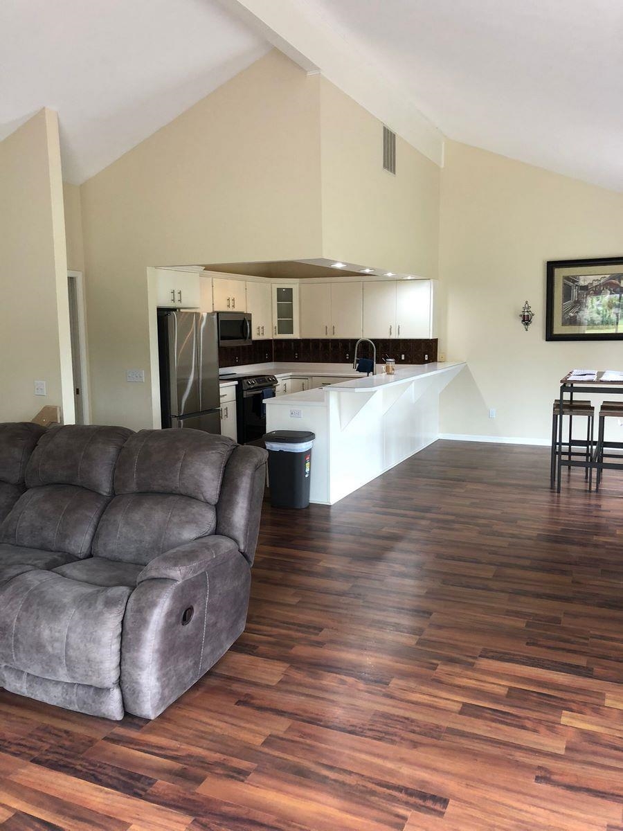 Living room with lofted ceiling and dark wood-style flooring