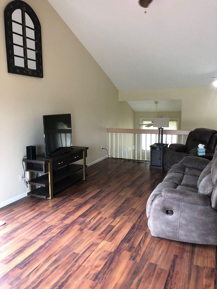 Living room with wood finished floors, vaulted ceiling, and ceiling fan
