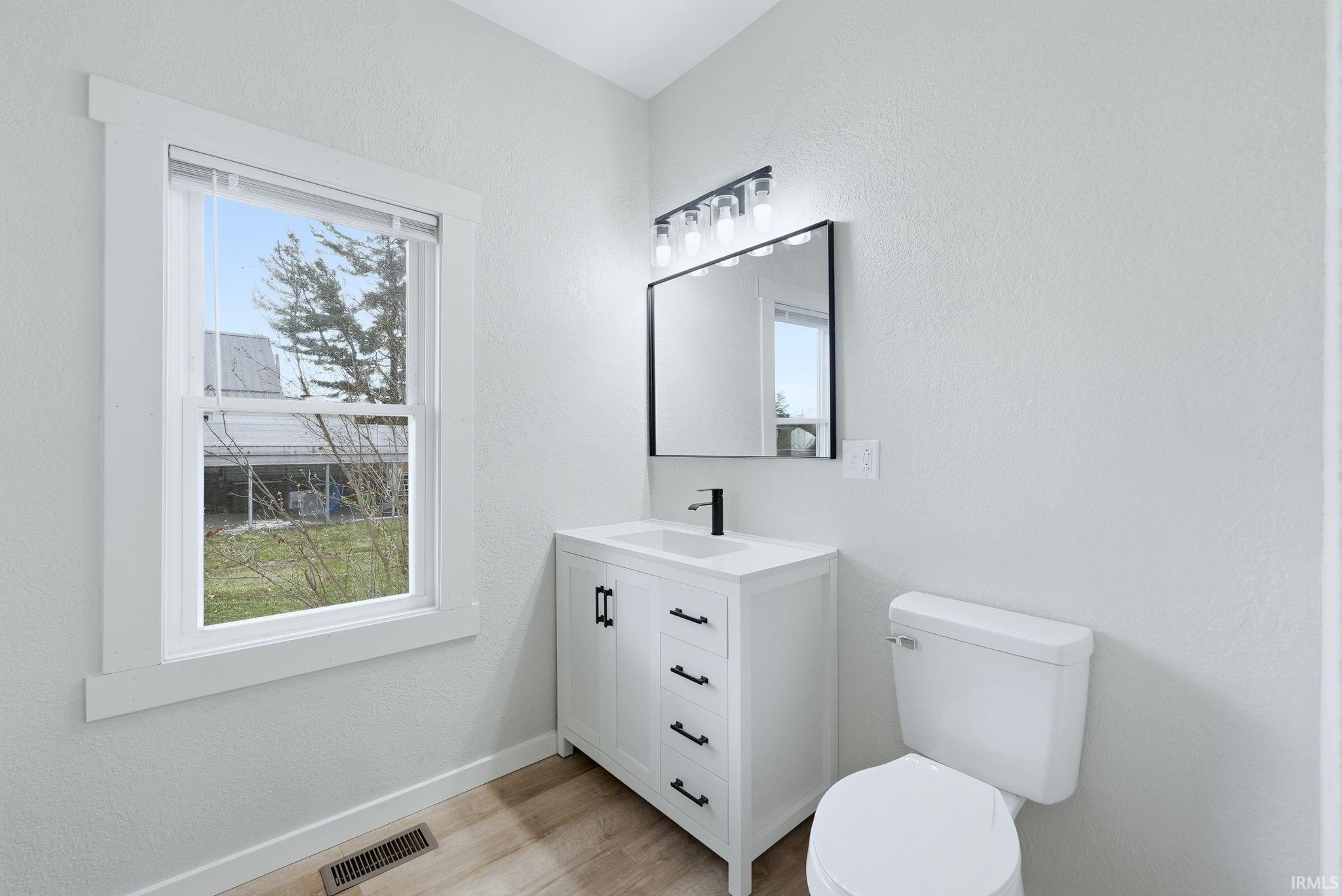 Bathroom featuring vanity, a textured wall, and light wood-type flooring