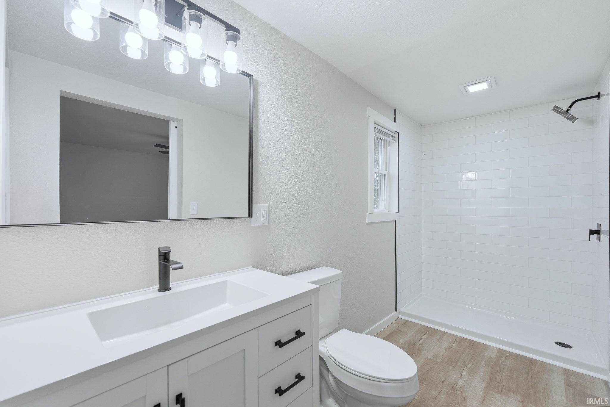 Bathroom with vanity, a stall shower, and light wood-style flooring