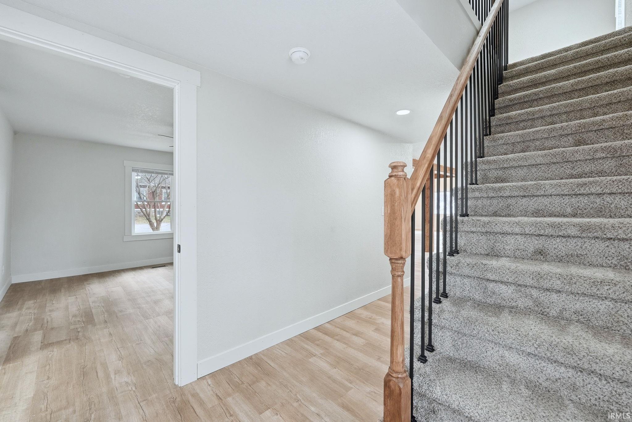 Stairs featuring wood finished floors and recessed lighting