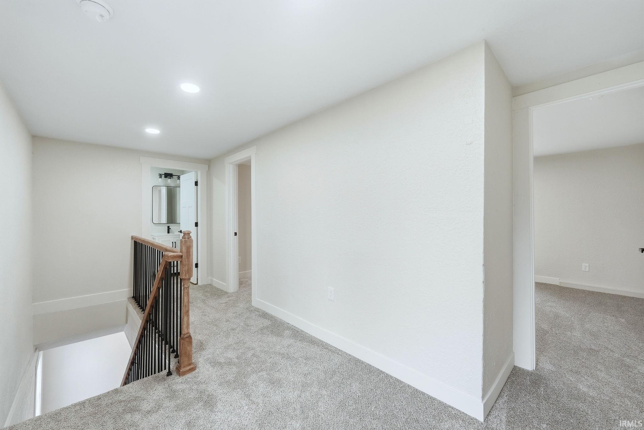 Hallway with an upstairs landing, light carpet, and recessed lighting