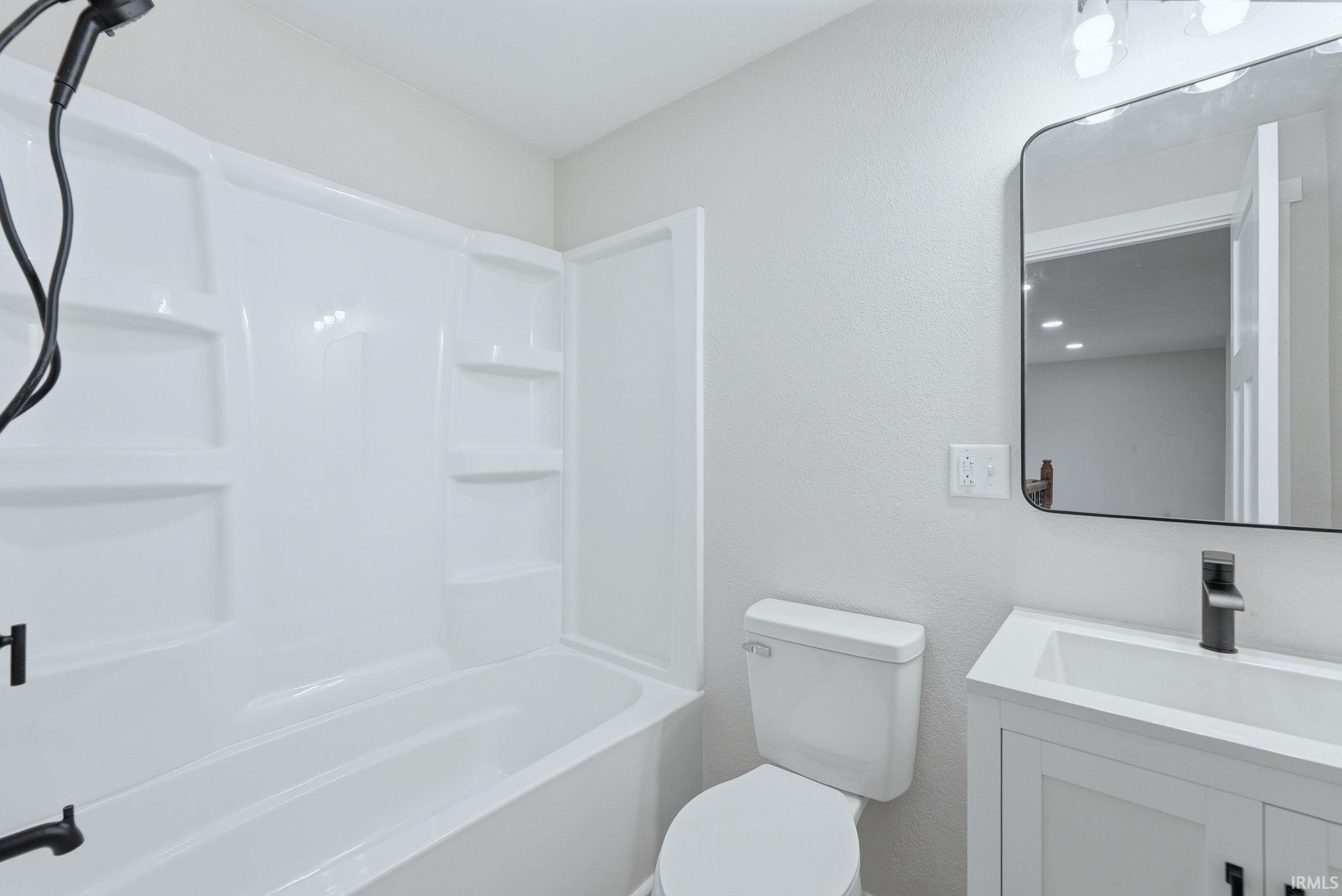 Bathroom featuring vanity, a textured wall, and  shower combination