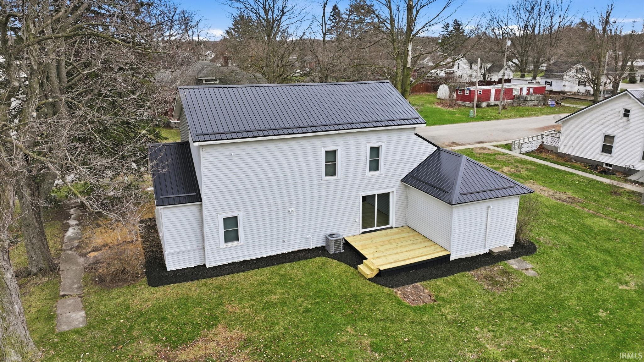 Back of property featuring a metal roof and a lawn