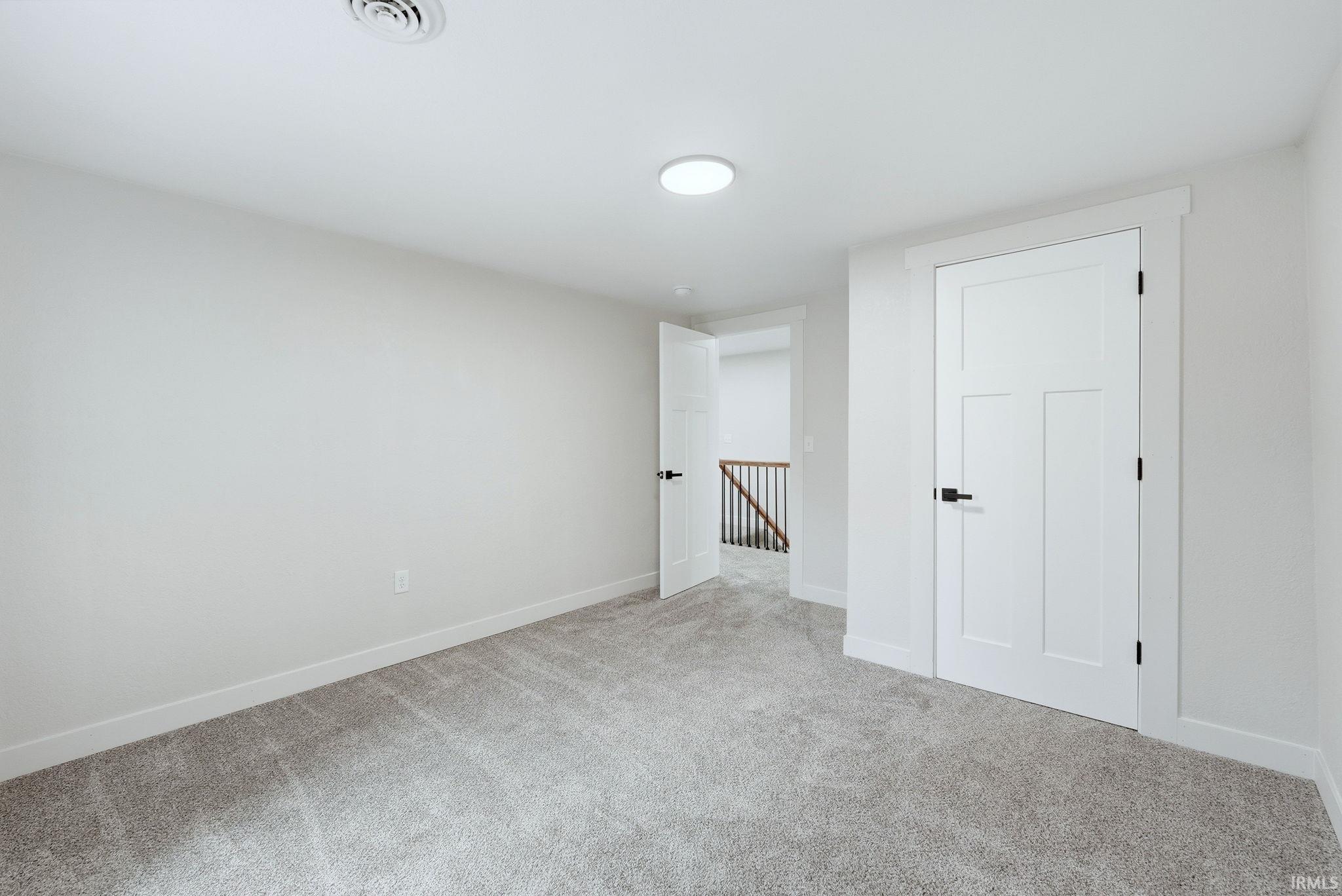 Unfurnished bedroom featuring light colored carpet and baseboards