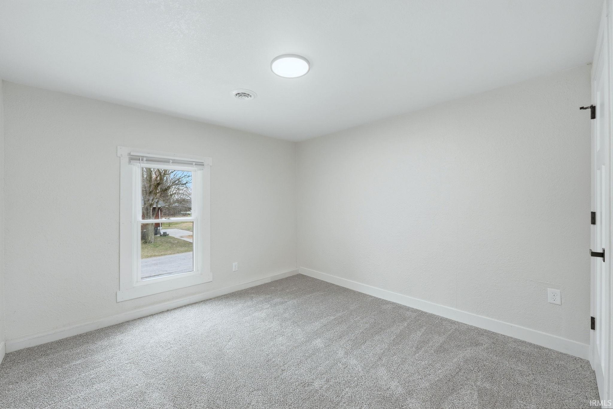 Spare room with baseboards and light carpet