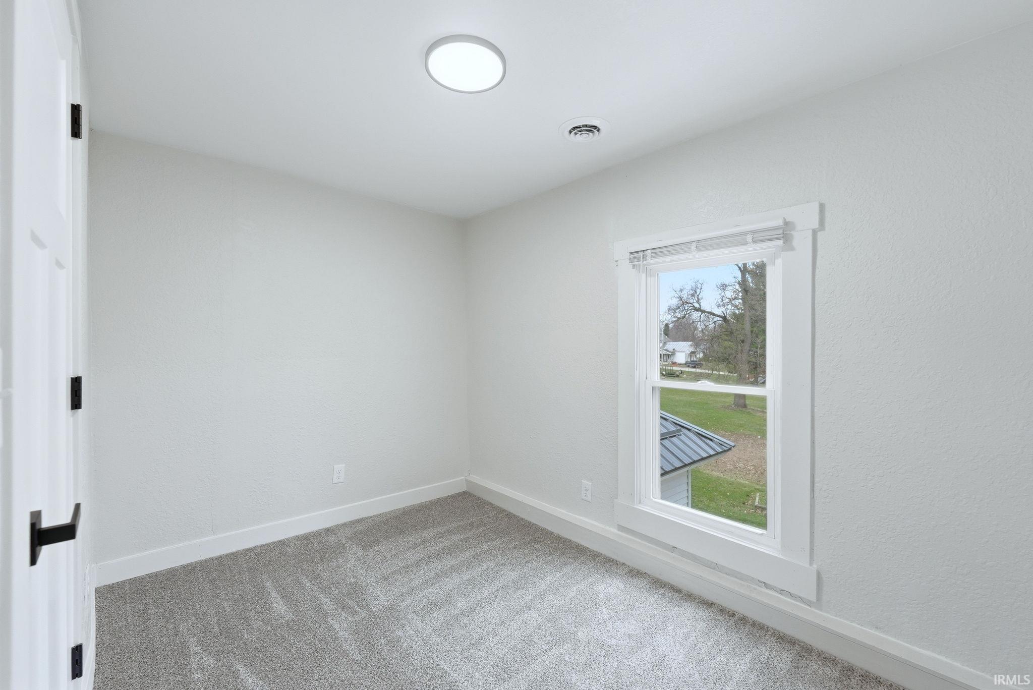 Spare room featuring baseboards and light carpet
