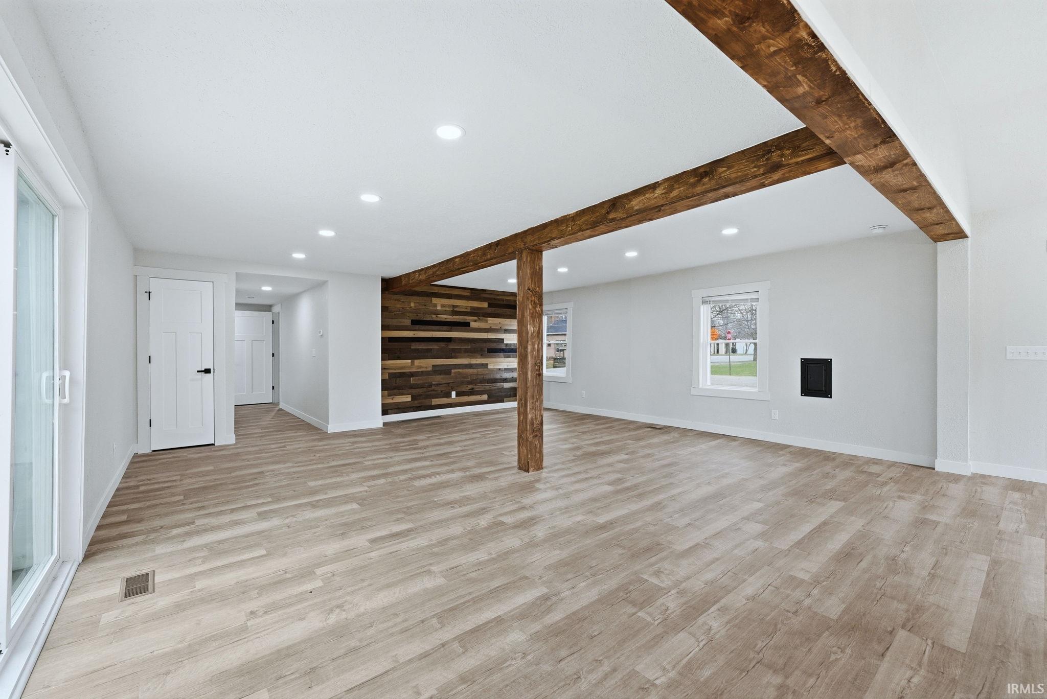 Below grade area featuring wood walls, recessed lighting, light wood-style floors, and an accent wall