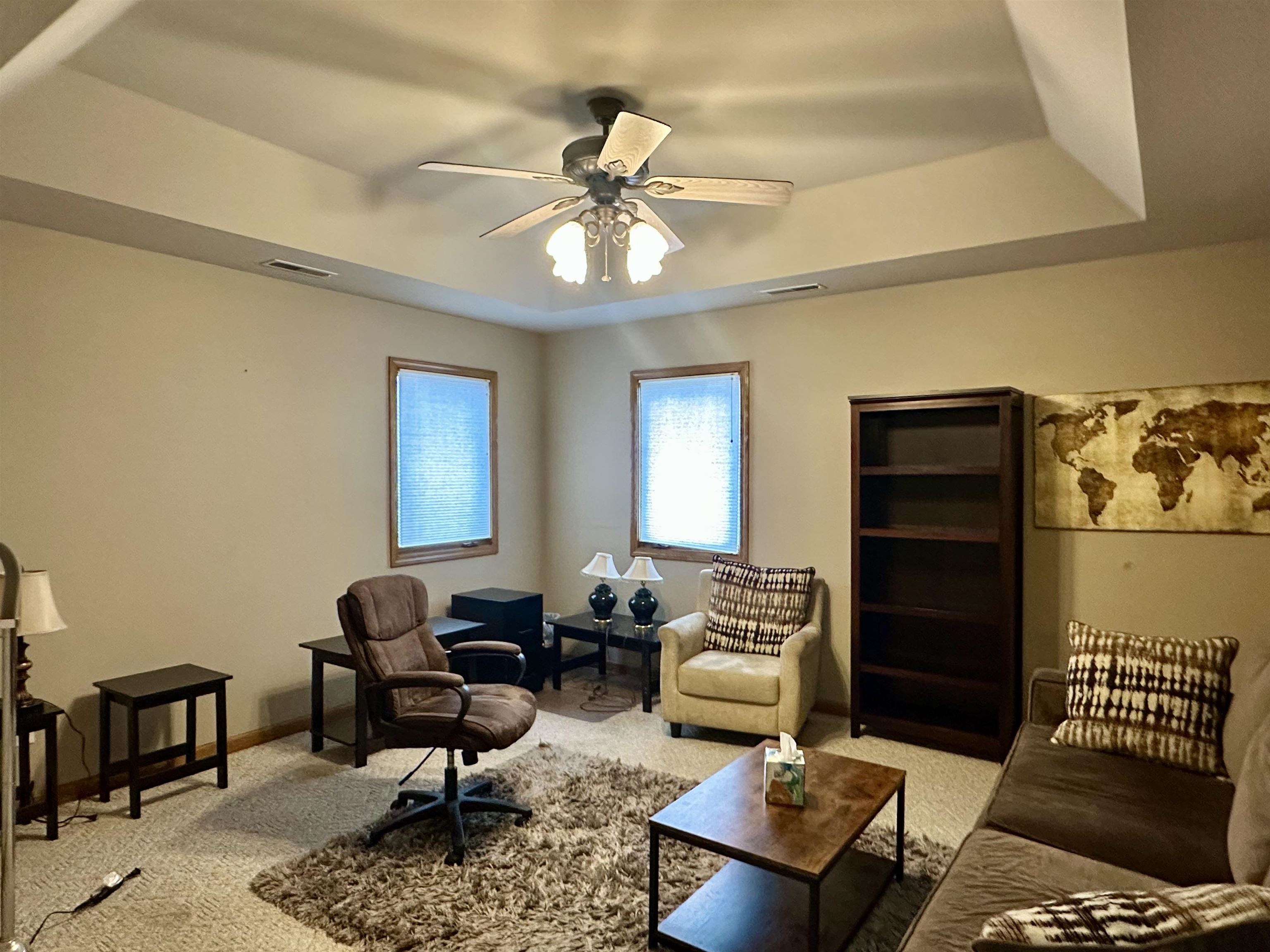 Office featuring a trayed ceiling, ceiling fan, and light carpet