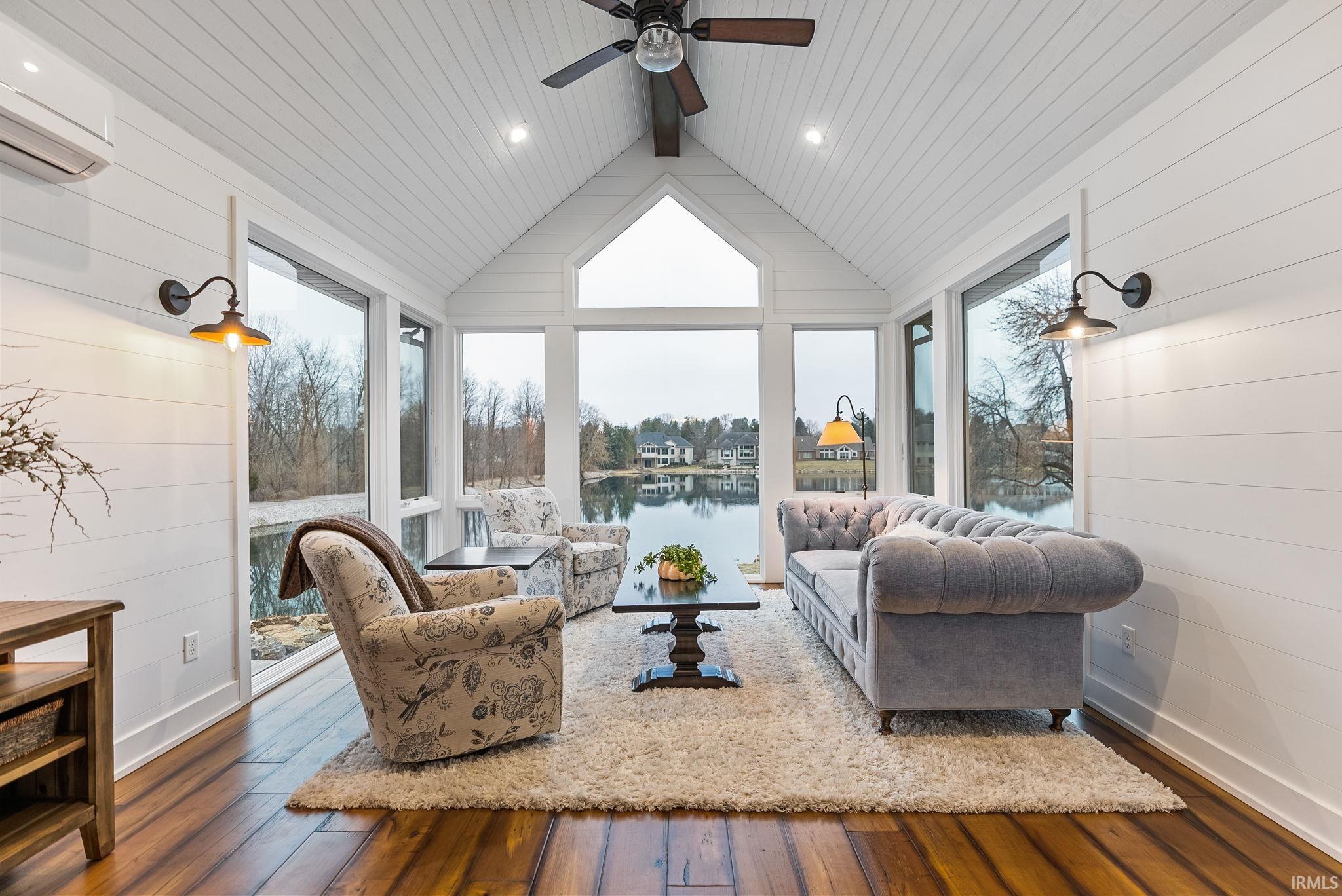Sunroom with wood walls, hardwood / wood-style floors, a water view, and beamed ceiling