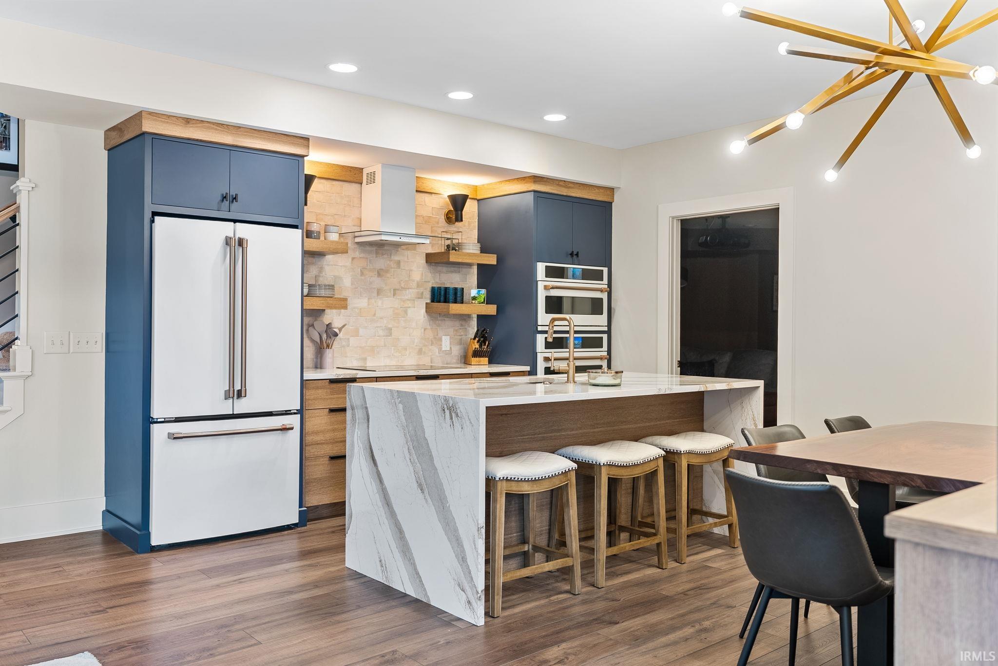 Kitchen with a kitchen breakfast bar, white appliances, open shelves, light stone counters, and dark wood-type flooring