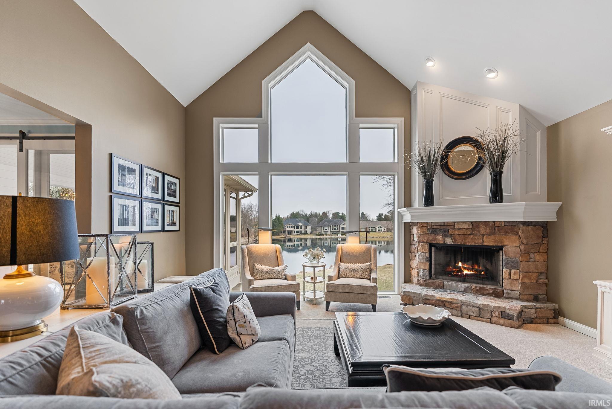 Carpeted living room with a fireplace, a high ceiling, and a water view