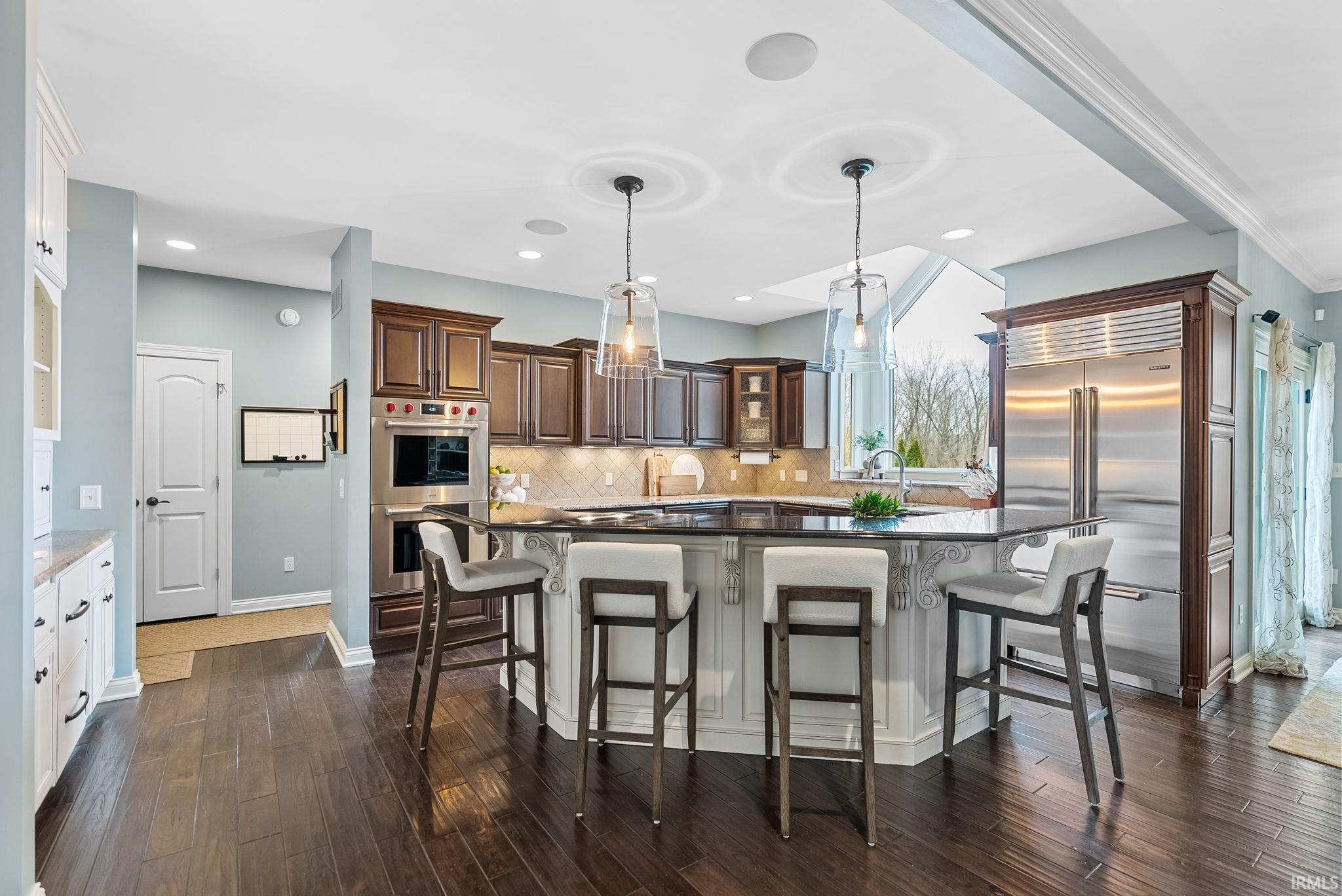 Kitchen with a kitchen bar, stainless steel appliances, a center island, dark wood finish cabinets, and dark wood-style floors