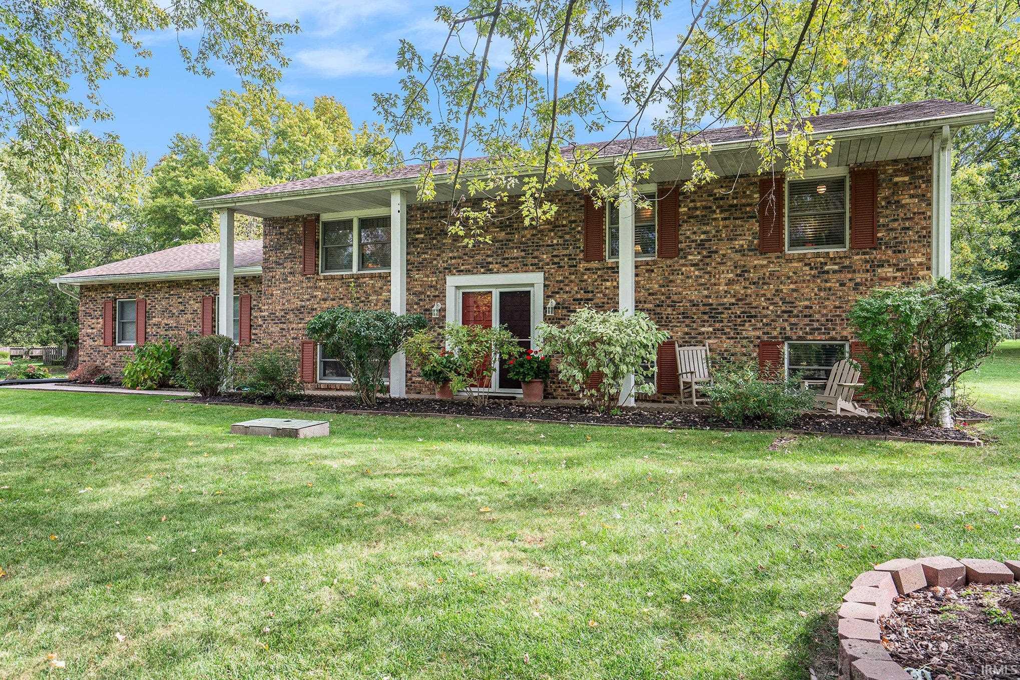 Raised ranch with a front lawn and brick siding