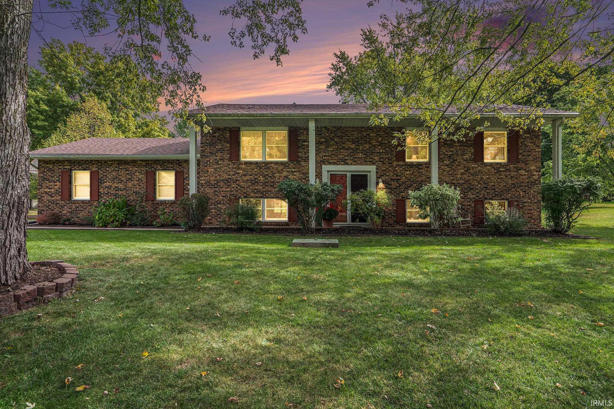 View of front facade with a front yard, brick siding, and covered porch