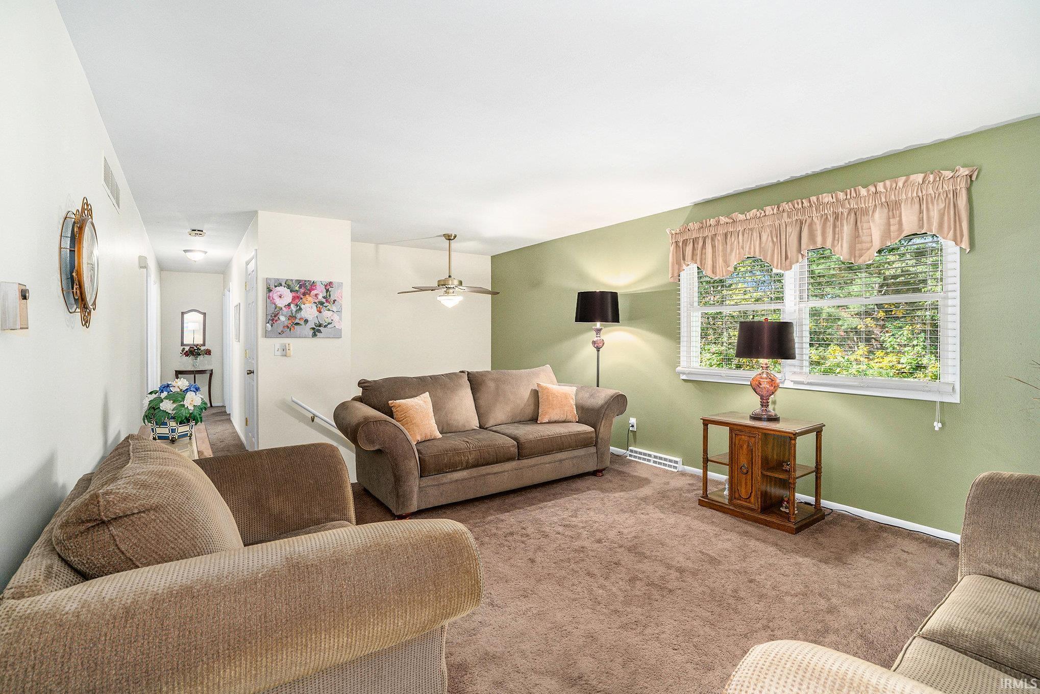 Carpeted living room with ceiling fan and baseboards