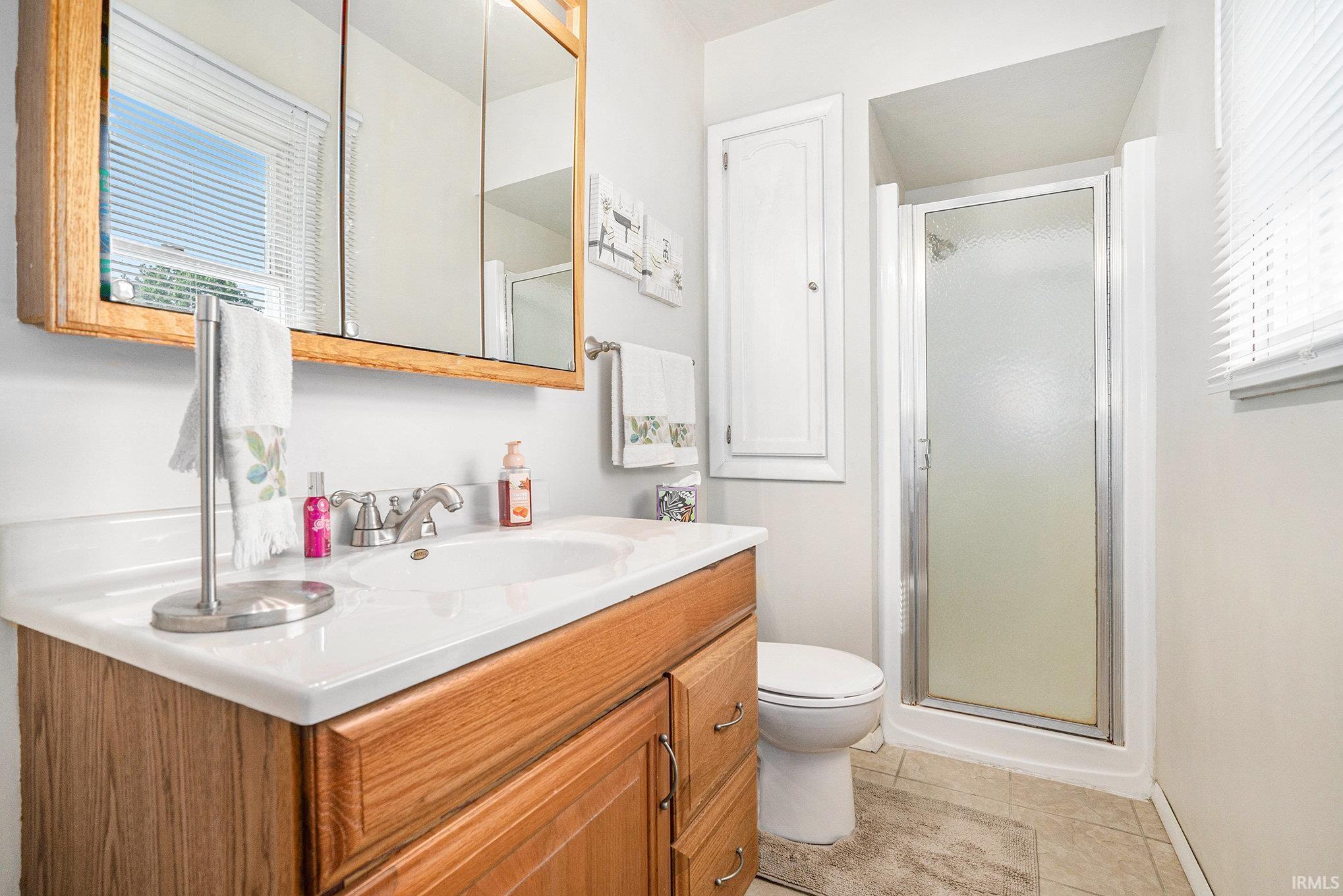 Bathroom featuring healthy amount of natural light, a shower stall, and vanity