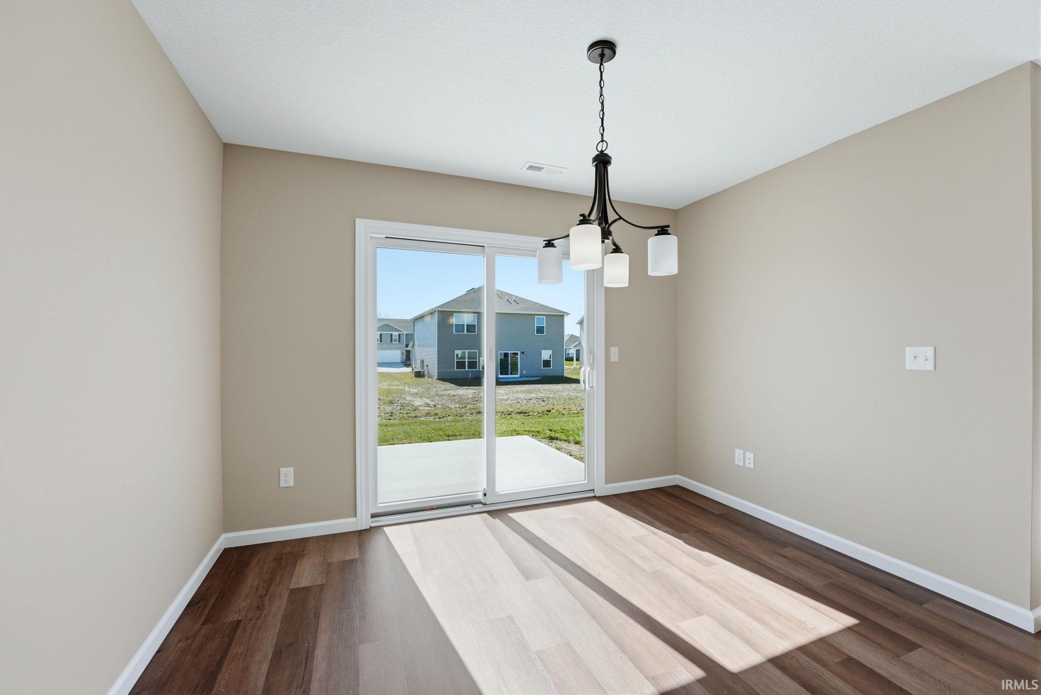 Unfurnished dining area featuring suspended lighting and dark wood-type flooring