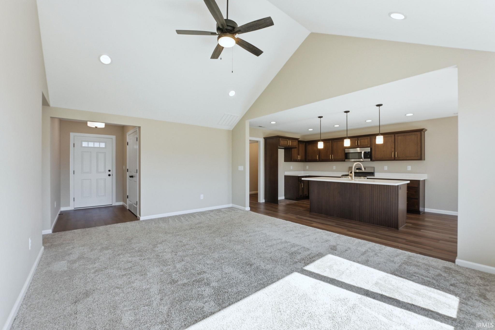 Unfurnished living room with a high ceiling, dark colored carpet, a ceiling fan, and recessed lighting