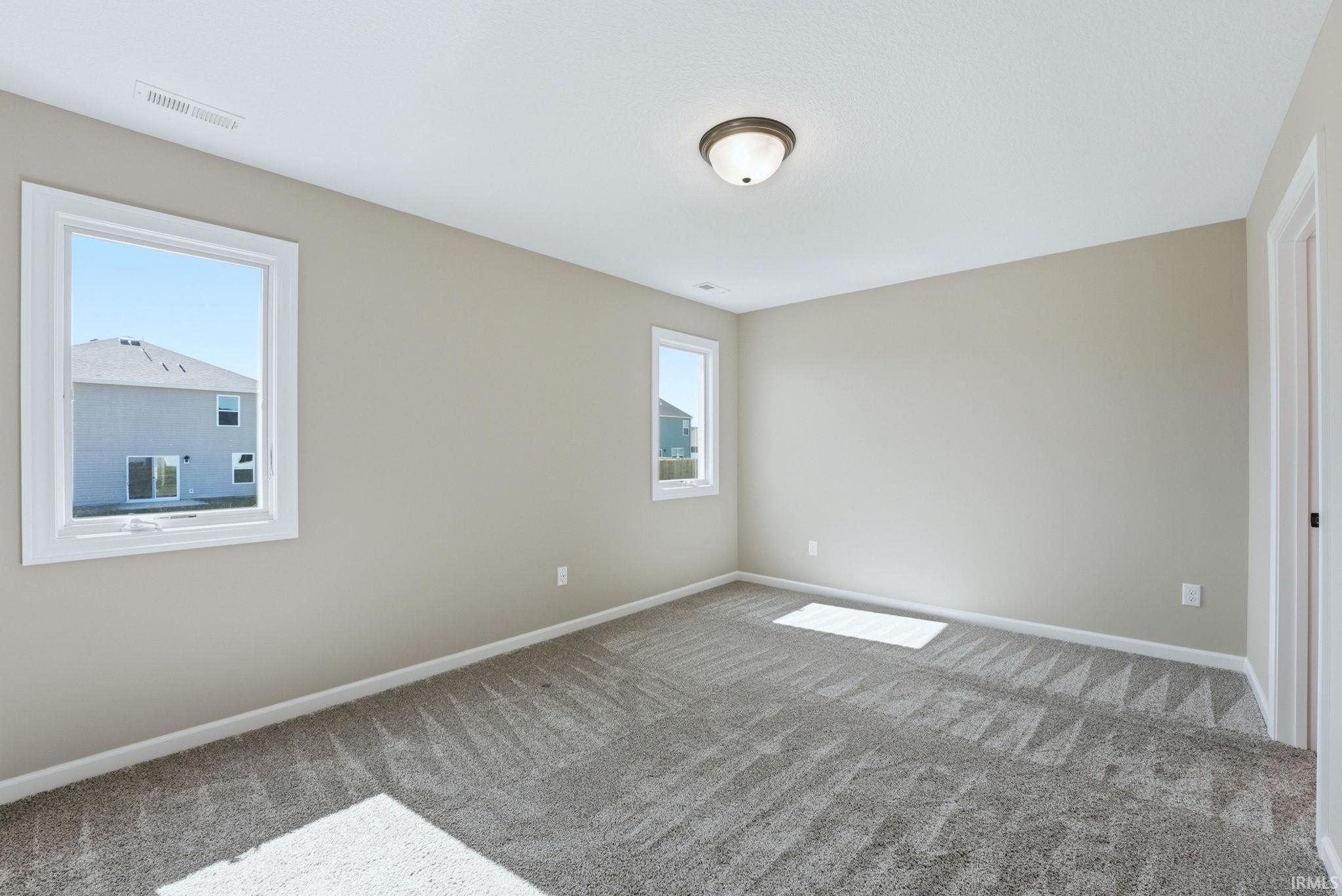 Spare room with baseboards and light colored carpet