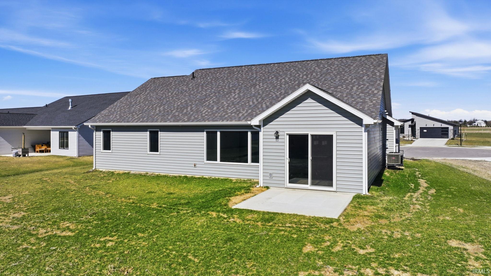 Back of house featuring a lawn and a shingled roof
