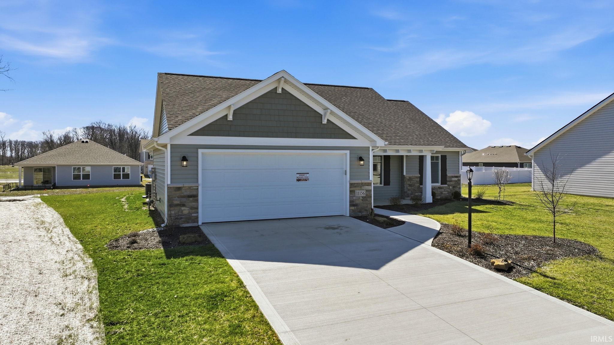 Craftsman-style house featuring a front lawn, stone siding, driveway, a garage, and roof with shingles