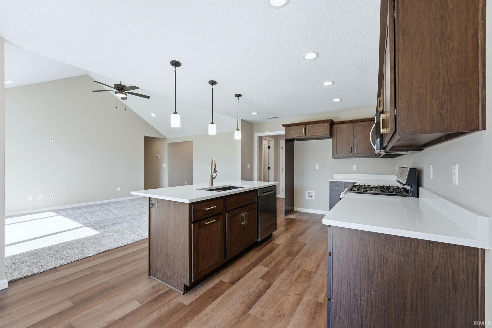 Kitchen with a kitchen island with sink, stainless steel appliances, hanging light fixtures, open floor plan, and a ceiling fan