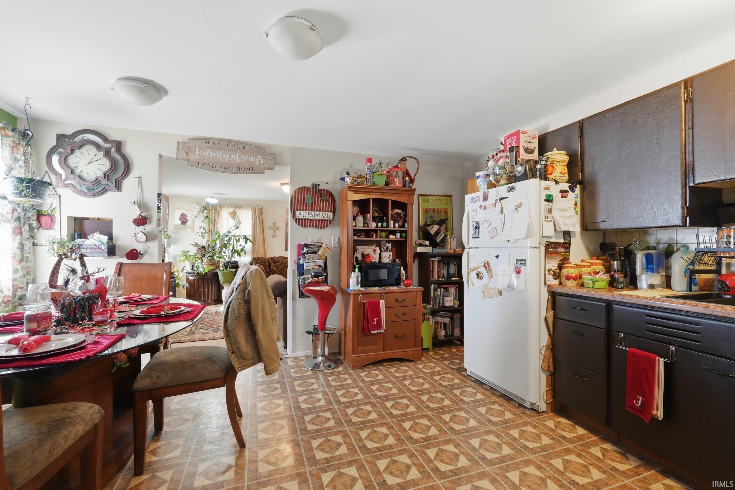 Kitchen featuring freestanding refrigerator, decorative backsplash, dark wood finish cabinets, black microwave, and light floors