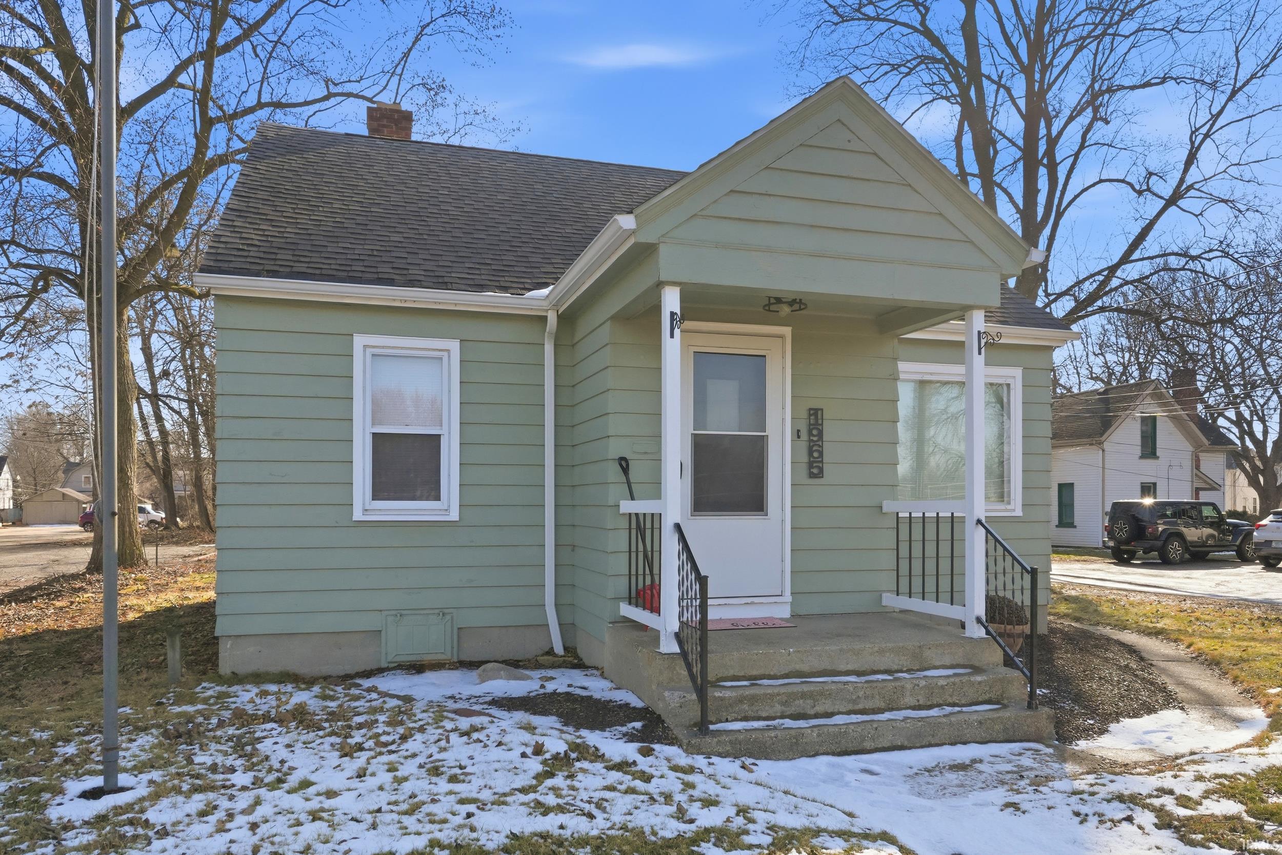 View of front of house featuring a shingled roof, a chimney, and covered porch