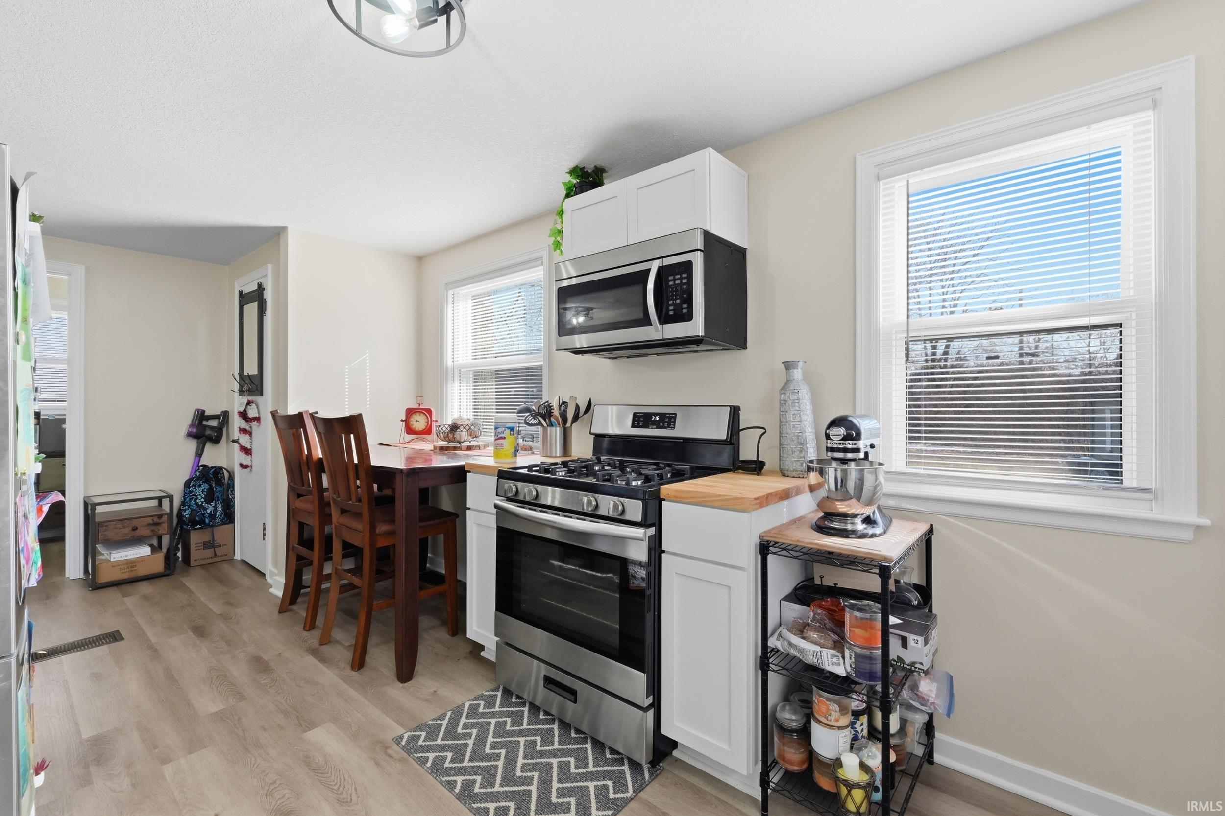 Kitchen with stainless steel appliances, butcher block counters, white cabinetry, and light wood finished floors
